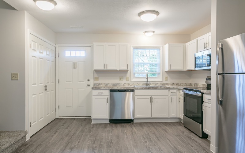 A kitchen with white cabinets and new flooring