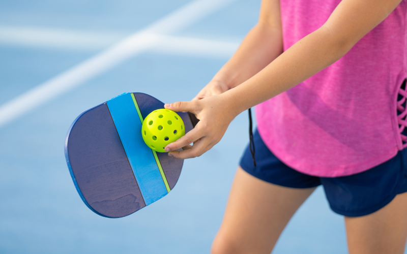 A person hitting a pickle ball with a paddle
